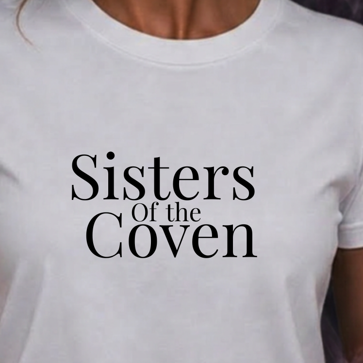 A white short-sleeve crewneck t-shirt with the text 'Sisters of the Coven' printed in black serif font on the chest, worn by a model against a dark smoky background.