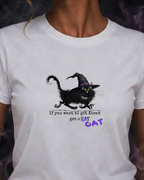 White t-shirt with a black cat graphic and text worn by a person against a dark background.